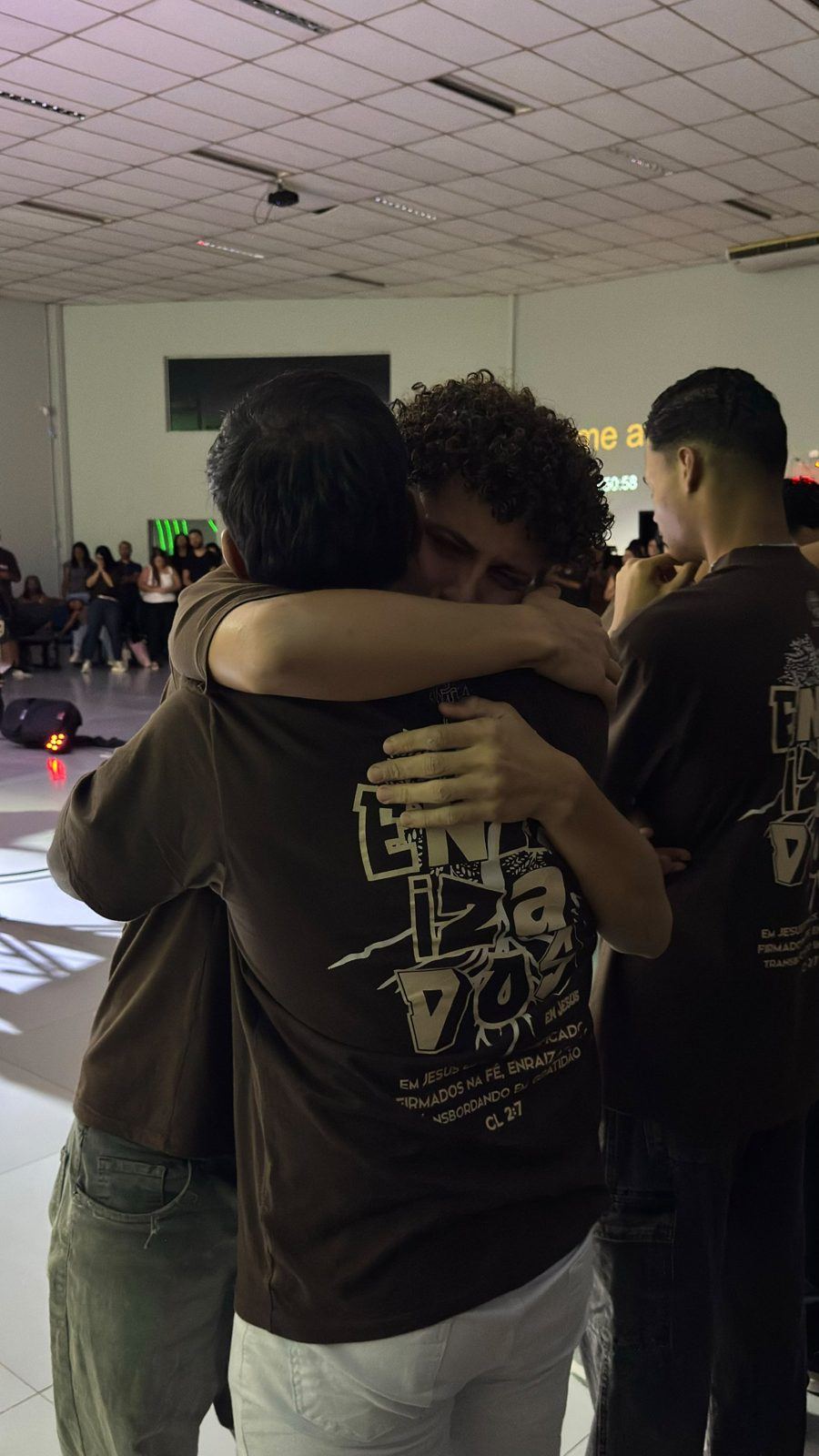 Dois jovens se abraçando com a camiseta Enraizados