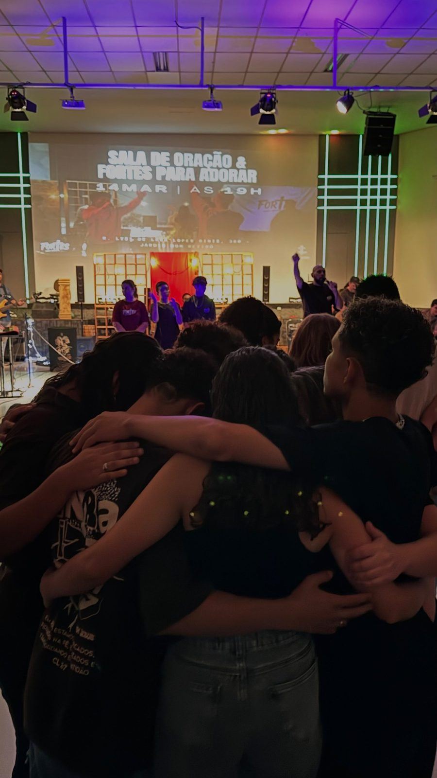 Jovens em adoração no templo iluminado de roxo
