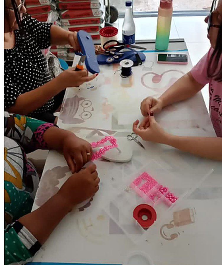 Participantes decorando chinelos com pedrarias