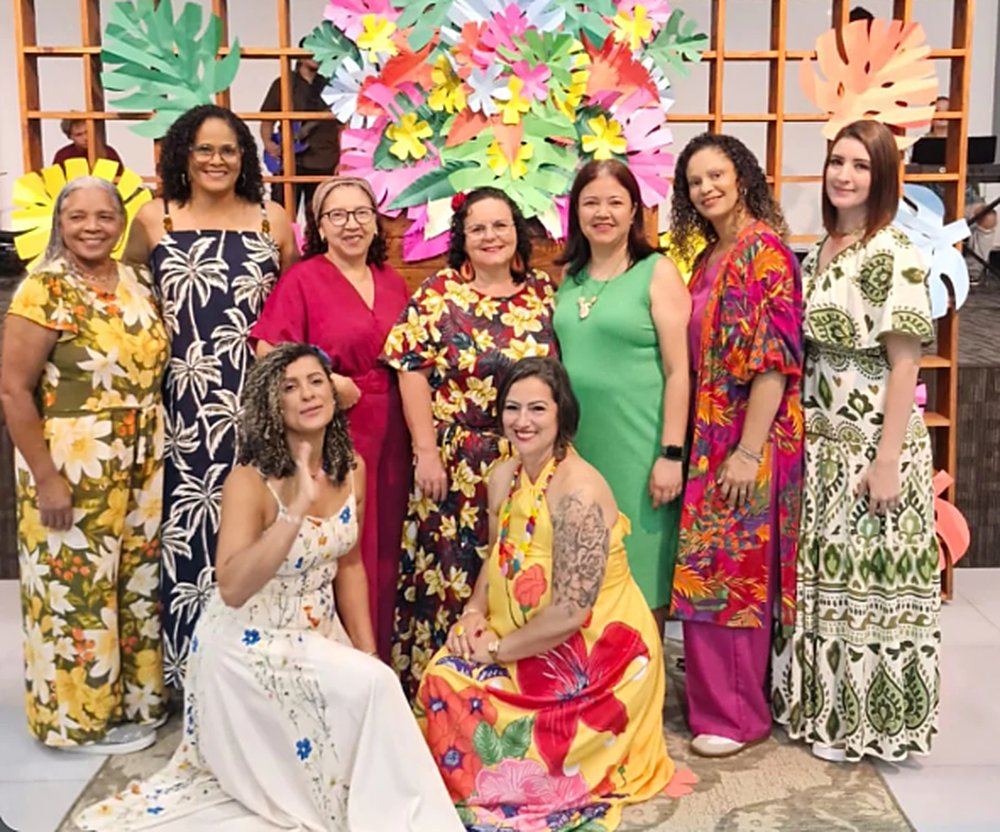 Grupo das Virtuosas em frente a um painel de flores